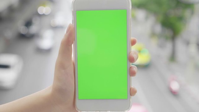 Hand holding telephone smart phone green screen chroma key traffic city blurred background