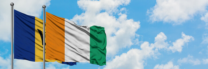 Barbados and Cote D'Ivoire flag waving in the wind against white cloudy blue sky together....