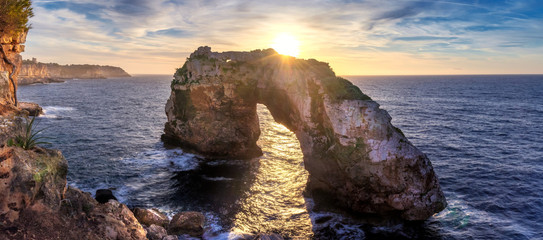 Natural arch in the mediterranean sea, sunrise with golden sunbeam and beautiful colourful sky, Santanyi, Mallorca, Spain. - obrazy, fototapety, plakaty
