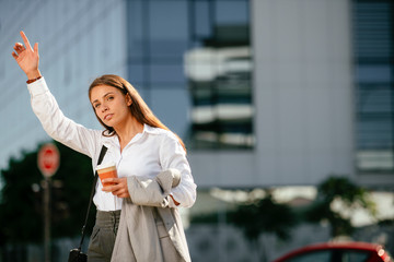 Young businesswoman calling taxi on street