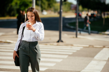 Young businesswoman drinking coffee on the street	