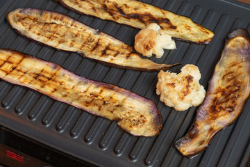 Grilled eggplant and cauliflower on electric grill, top view. Vegetarian dish of aubergine and vegetables. Healthy diet