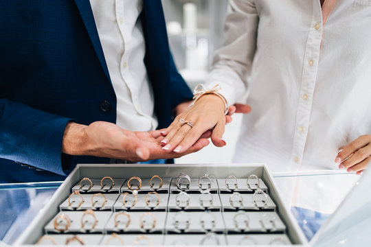 Beautiful couple enjoying in shopping at modern jewelry store. Close up shot of woman's hand with gorgeous expensive ring and bracelet.