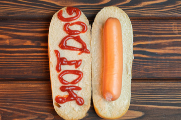 Hot dog on dark wooden background. Fried sausage and bread