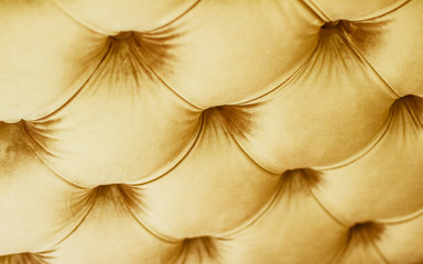 Golden luxury velour quilted sofa upholstery with buttons, elegant home decor texture and background