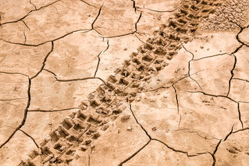 Traces of motorcycles on dry cracked ground as background