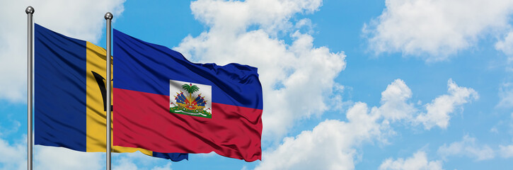 Naklejka premium Barbados and Haiti flag waving in the wind against white cloudy blue sky together. Diplomacy concept, international relations.