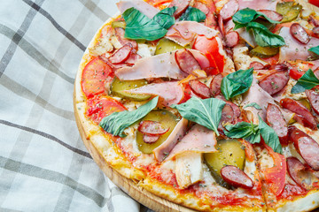 Italian, homemade sliced pizza with meat, salami, cucumber, basil and hot pepper on a wooden table. Top view food with copy space. Flat lay