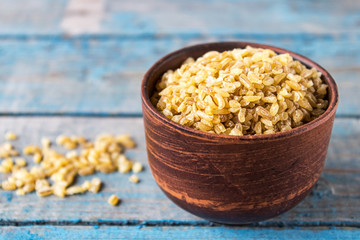 Dry bulgur grain in a bowl. A pile of raw grain Bulgur porridge. Healthy, dietary, vegan, gluten free product. Healthy eating concept. Organic product made from wheat grains.
