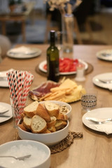 Table set for dinner party with plates, bread, ice, paper straws and spread. Selective focus.