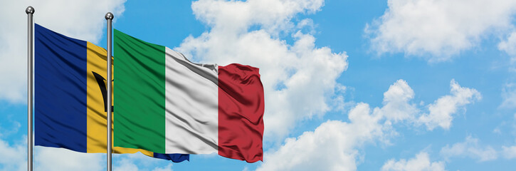 Obraz premium Barbados and Italy flag waving in the wind against white cloudy blue sky together. Diplomacy concept, international relations.