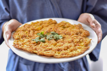 Omelet popular breakfast for Thai people in white dish with holding hand.