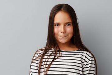 Fototapeta premium Little girl making a grimace over a grey background