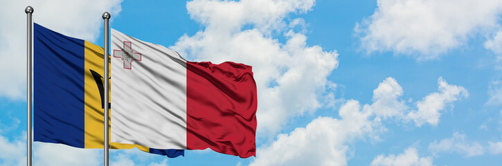 Barbados and Malta flag waving in the wind against white cloudy blue sky together. Diplomacy concept, international relations.