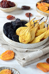 Dried pears and prunes on a white vane background