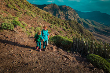 cute boy and girl travel in mountains at sunset