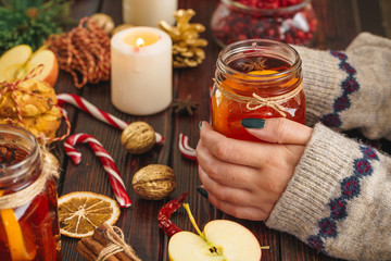 Cup of mulled wine in woman's hands on wooden table