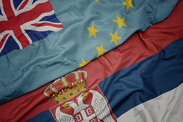 waving colorful flag of serbia and national flag of Tuvalu .