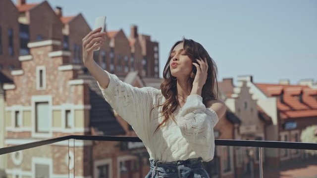 happy girl taking selfie and sending air kiss 