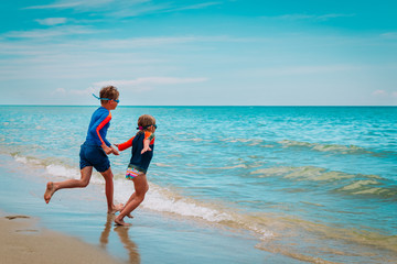 happy boy and girl run and play with water on beach