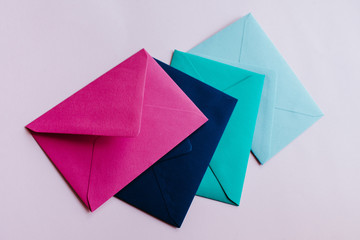Colored paper envelopes on a light background. New mail, write message. Send and receive letter. Postal delivery service. Blank envelope, empty space. People communication, paperwork. Envelope closeup