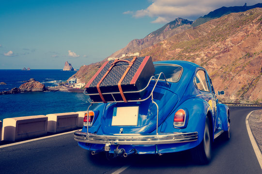 Retro car with luggage on the roof rack on the coastal road. Travel, vacation concepts.retro, vintage color