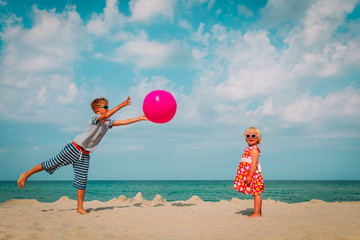 kids play with ball on beach, boy and girl have fun at sea