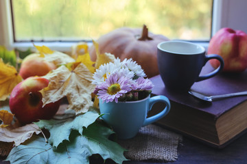 cup of coffee, autumn leaves and apples on a window background.