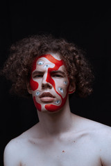 Man studio portrait with makeup for halloween. Abstraction on the face and many eyes.