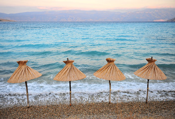 Umbrellas on the beach of Krk island on sunset