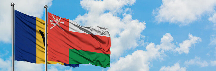Barbados and Oman flag waving in the wind against white cloudy blue sky together. Diplomacy concept, international relations.