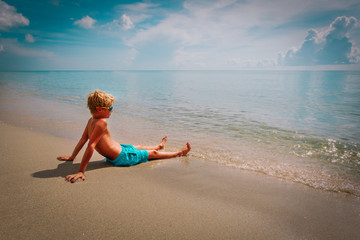 young boy relaxed on beach, kid looking at sea on vacation