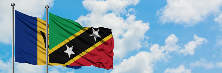 Barbados and Saint Kitts And Nevis flag waving in the wind against white cloudy blue sky together. Diplomacy concept, international relations.