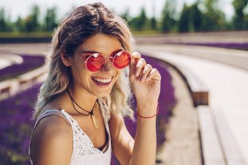 Girl with beautiful teeth in sunglasses laughs joyfully in the park - 297571441