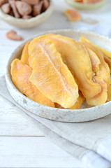 Dried mango in a plate on a white wooden background