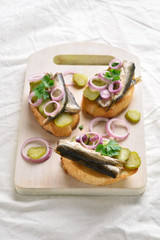 Sandwiches with sprats, marinated cucumber and onion
