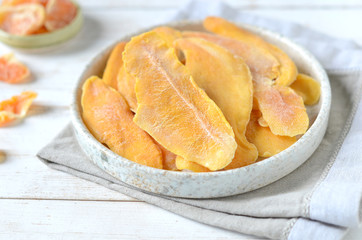 Dried mango in a plate on a white wooden background
