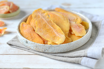 Dried mango in a plate on a white wooden background