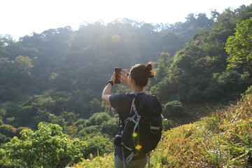 Woman hiker taking pictures with smartphone in autumn forest