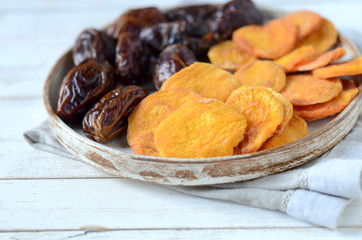 Dried dates and dried apricots on a white wooden background