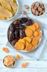 Dried dates and dried apricots on a white wooden background