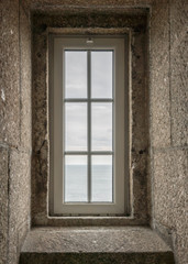 Fototapeta na wymiar view of the ocean through a lighthouse window in the stone staircase