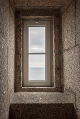 Fototapeta na wymiar view of the ocean through a lighthouse window in the stone staircase