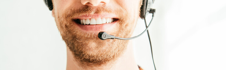 panoramic shot of bearded broker in headset smiling in office