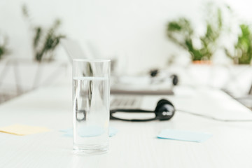 selective focus of glass with water near headsets in office