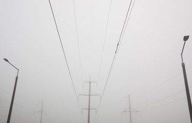 The electric pole and wires in front of gray foggy cloud. Concept of minimalist photo