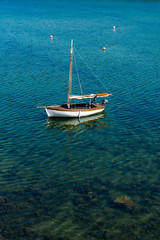 small sailboat anchored in a harbor at low tide