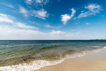Fototapeta na wymiar gentle waves on an empty sandy beach with a calm ocean