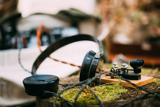 Russian Soviet Portable Radio Transceiver Used By USSR Red Army Signal Corps In World War Ii. Headphones And Telegraph Key Are On A Forest Stump