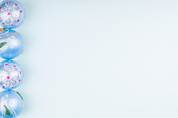 Glitter Christmas ball toys with winter ornament on blue paper background. Concept of Xmas and New Year greeting card. Top view. Copy space.